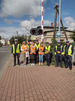 Zdjęcie przedstawia umundurowanych policjantów Ruchu Drogowego w Gryficach stojących w szeregu z pracownikami kolei i funkcjonariuszami SOK w Ramach akcji Bezpieczny Przejazd &quot;Szlaban na ryzyko&quot;