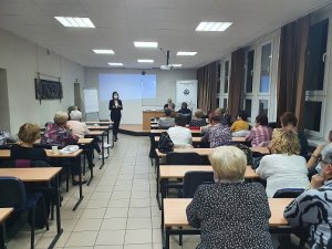 Zdjęcie przedstawia pracownika ZUS prowadzącego wykład na sali Zachodniopomorskiej Szkoły Biznesu w Gryficach. Na zdjęciu widać seniorów, oraz policjantów