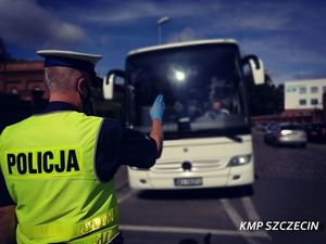 Zdjęcie przedstawia policjanta ruchu drogowego zatrzymującego autobus do kontroli przy użyciu tarczy do zatrzymania pojazdów. Jest to zdjęcie poglądowe.