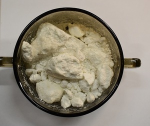 Zdjęcie przedstawia naczynie koloru dymnego z zawartością białego proszku tj. amfetaminy