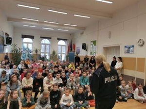 Zdjęcie przedstawia umundurowanego policjanta na spotkaniu profilaktycznym z uczniami ze Szkoły Podstawowej nr 1 w Płotach