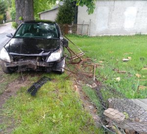 Samochód Opel koloru czarnego, który wjechał w ogrodzenie posesji