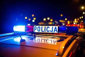 Zdjęcie poglądowe przedstawiające światła radiowozu oznakowanego Policji w tle widać rozmyte światłą miasta.