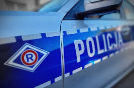 Zdjęcie poglądowe przedstawia radiowóz służbowy z napisem Policja. Na nadkolu pojazdu widoczny znak w kształcie rombu z literą R.