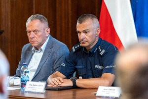 Zdjęcie przedstawia insp. Szymona Sędzika siedzącego przy stole w umundurowaniu służbowym.