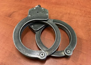 Zdjęcie poglądowe przedstawiające kajdanki szczękowe leżące na blacie stołu w kolorze ciemny buk.